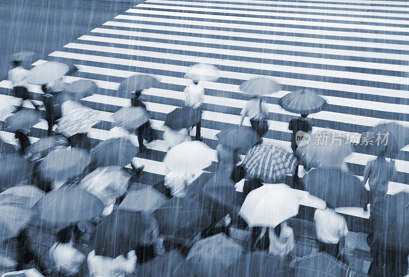 繁忙的人行横道场景在雨天与模糊运动