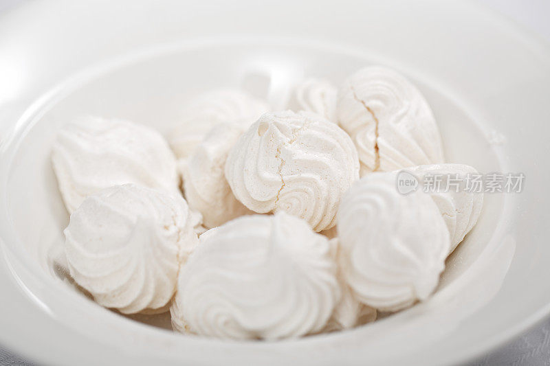 白色背景上放着白色蛋白酥饼的白色碗。