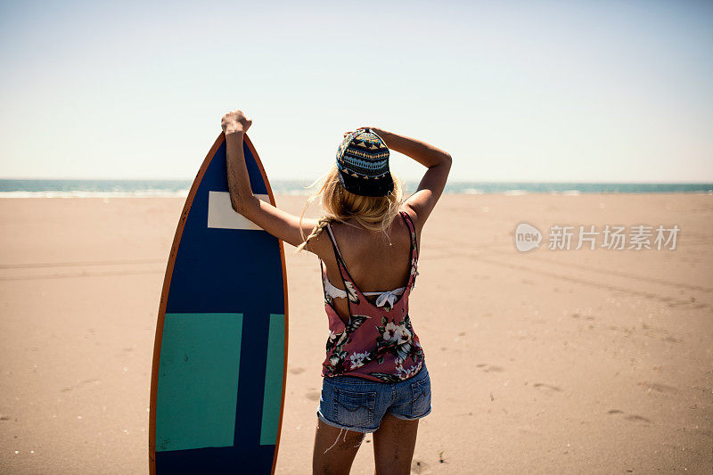 美丽性感的年轻女子冲浪女孩的后视图在日落或日出的海滩上白色冲浪板穿着比基尼