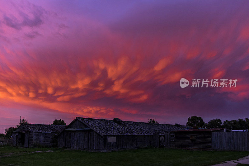 日落时分，古老的农场建筑上空，五颜六色的乳房云