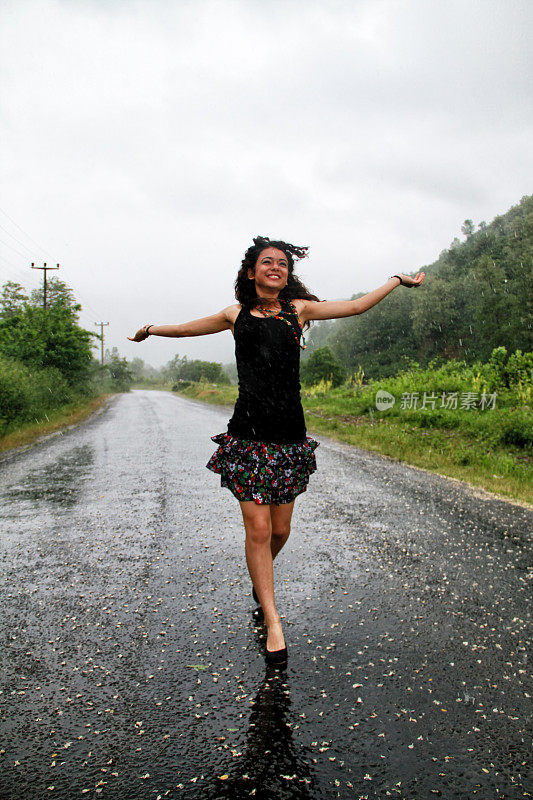 年轻的笑着女人在热带雨中奔跑。