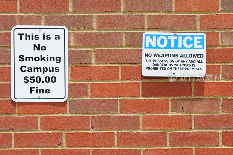 校园墙上的吸烟和武器警告标志