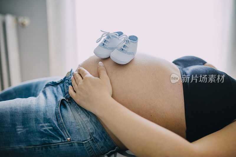 宝宝的鞋子放在怀孕的肚子上