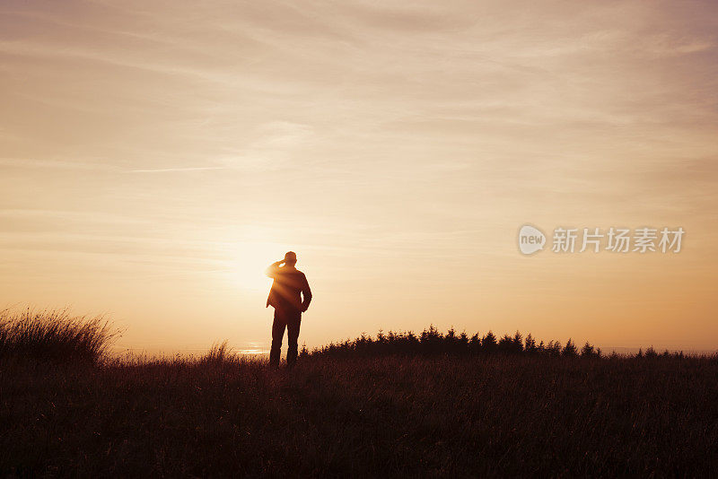 一个人站在乡村里凝视着日落