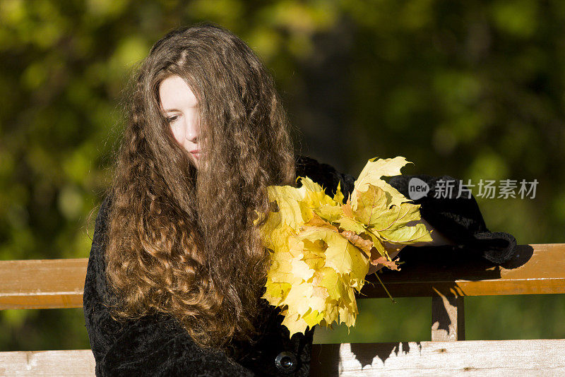 悲伤的女孩半掩着脸，长发托着秋叶