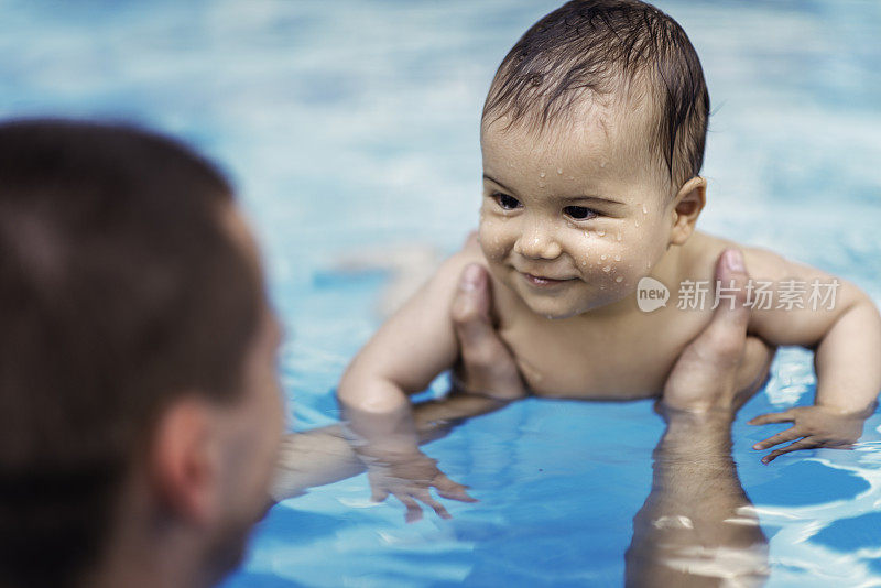 在游泳池里微笑的男婴