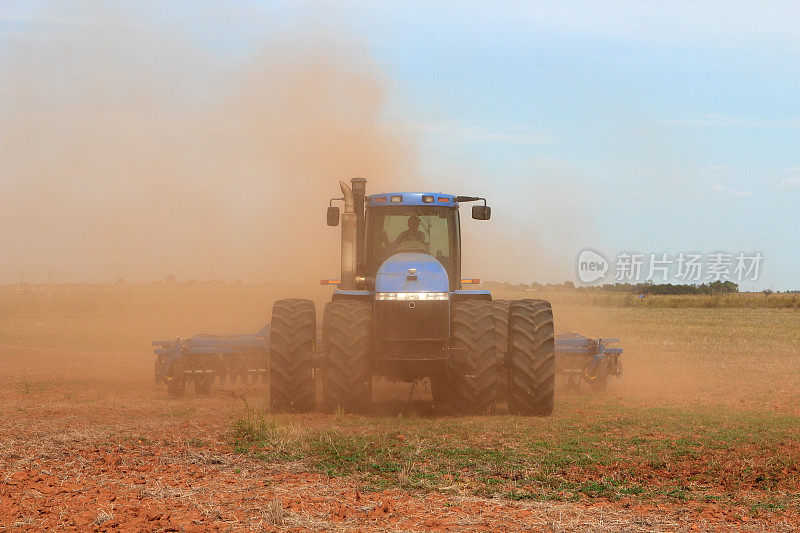 农业:在田里使用拖拉机和圆盘犁的农民