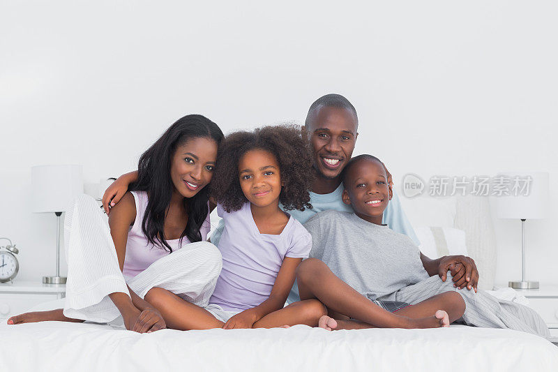 一家人坐在床上对着镜头微笑