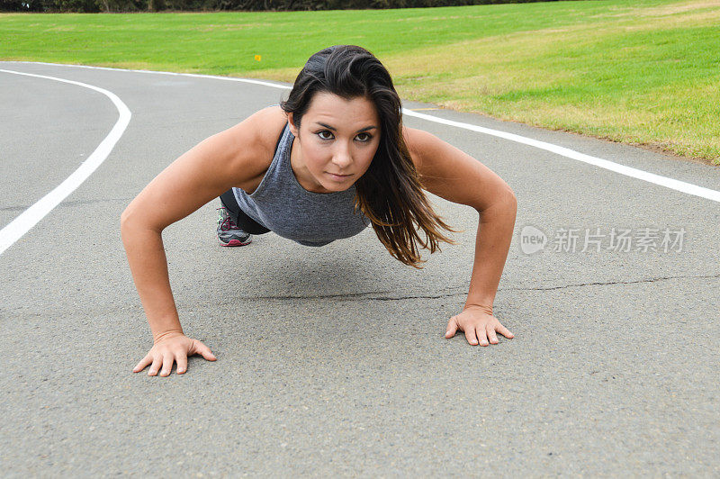 运动瘦女人在跑道上做俯卧撑
