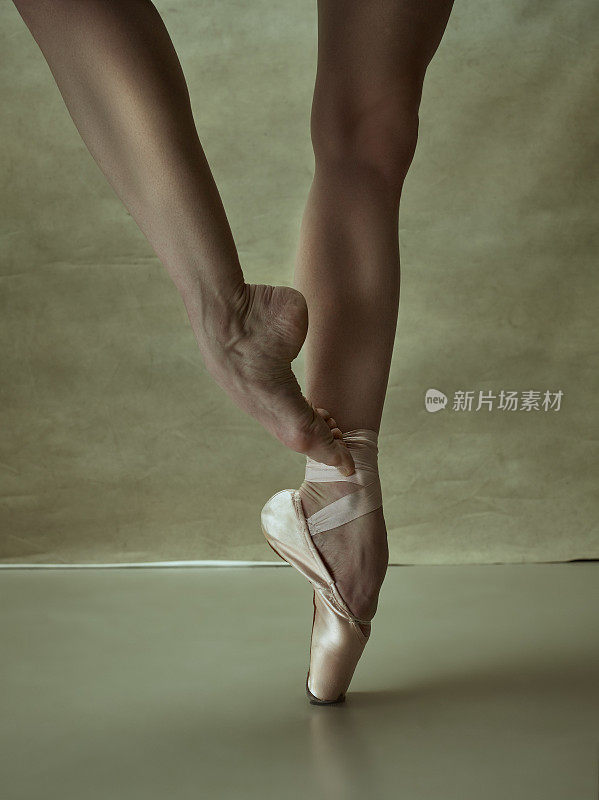 芭蕾舞女演员穿着尖头鞋在灰色地板上摆姿势