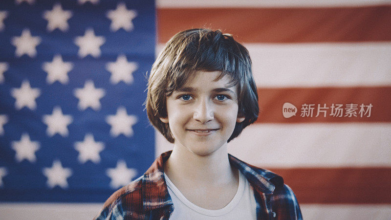 一个男孩站在美国国旗前