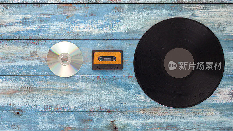 黑胶唱片，cd盘和音频磁带在一个古老的蓝色背景