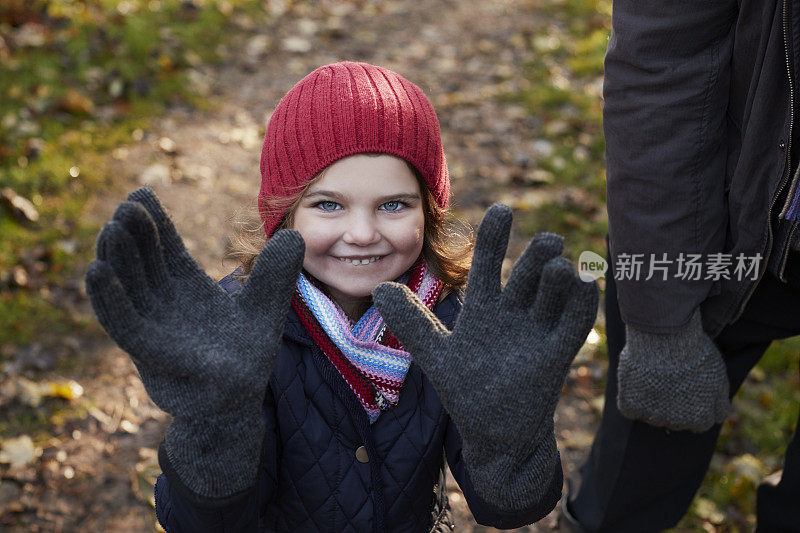 孙女戴着爷爷的手套在秋天散步