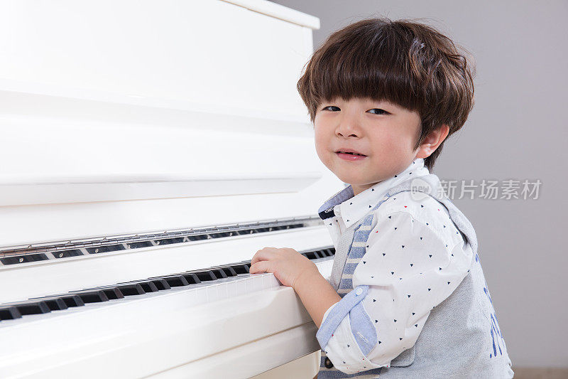 快乐的亚洲华人小男孩在家里弹钢琴