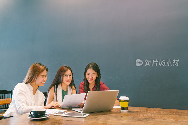 三个美丽的亚洲女孩使用笔记本电脑在团队商务会议，同事或大学生，创业项目讨论或团队头脑风暴的概念，咖啡馆或现代办公室的复印空间