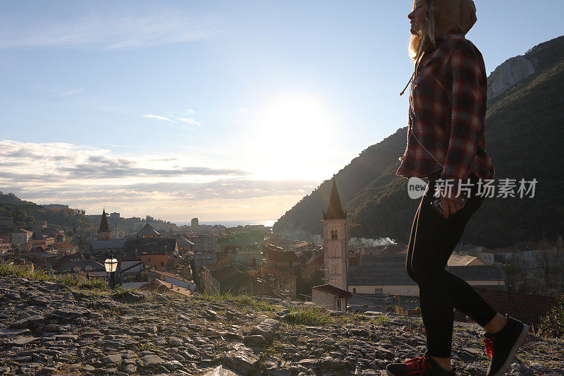 日出时，年轻女子在村庄和海面上行走