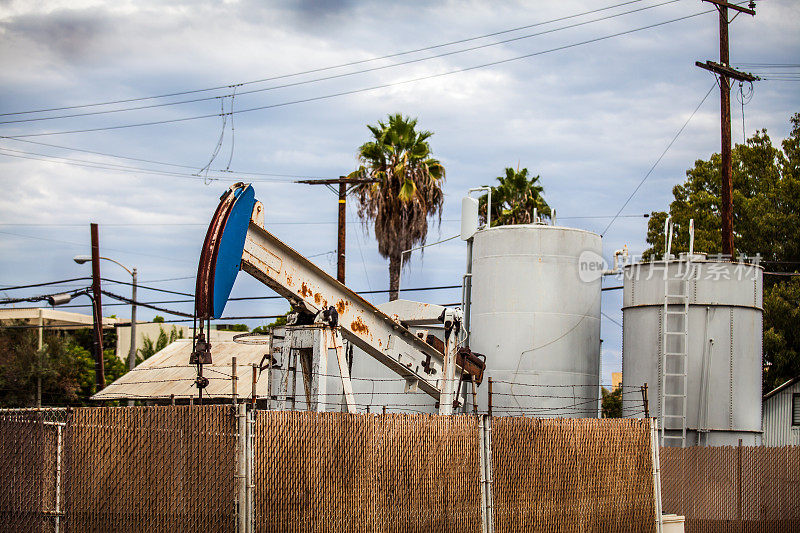 加利福尼亚州长滩的一个篱笆后面的石油抽油机和储油罐。