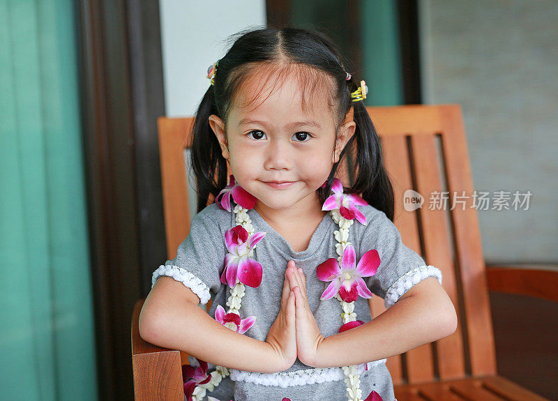 泰国小女孩“Sawatdee”坐在木椅上。