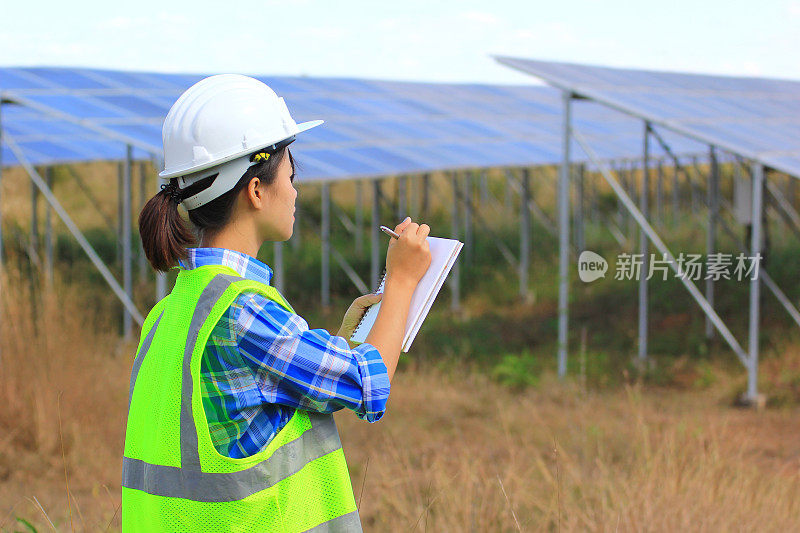 年轻的女工程师在太阳能发电厂检查太阳能电池板