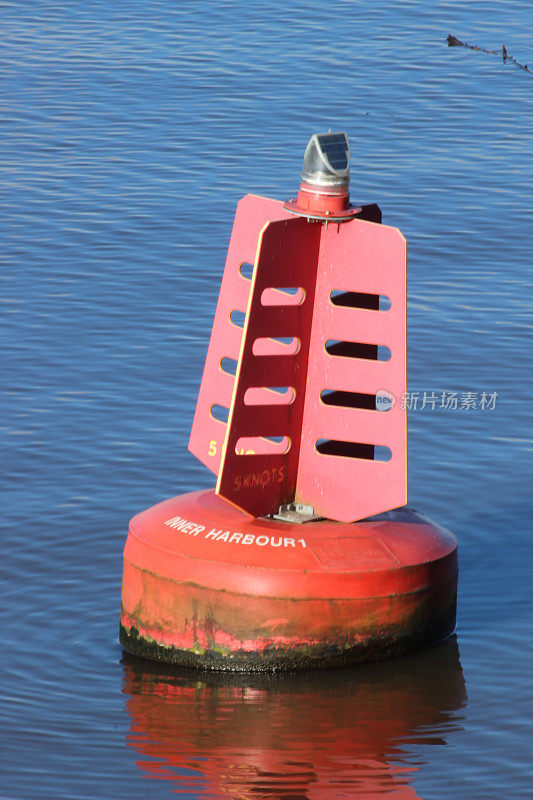 一个红色的5节航速标志浮标漂浮在平静的蓝色水面上