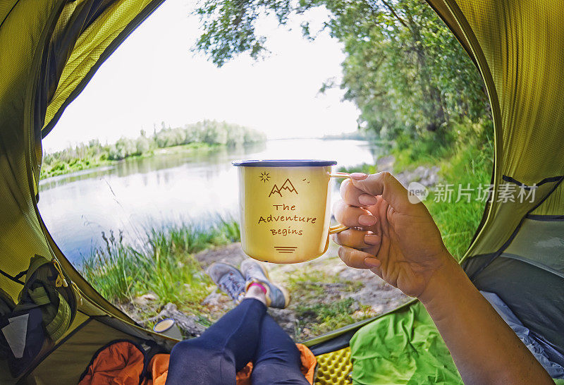 年轻女子坐在帐篷里喝茶，看着德斯纳河
