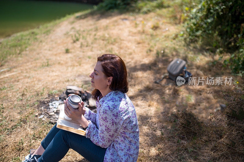 一个年轻女子坐在夕阳下的湖上看书。