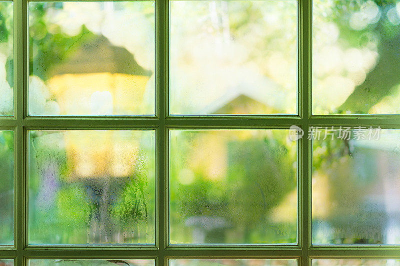 绿色的窗户与凝结模糊的家和灯在花园的背景。现象与自然概念。