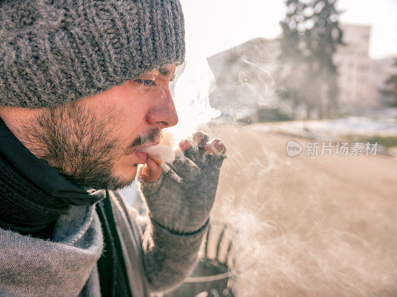 一个年轻男子吐出大量香烟烟雾的特写镜头