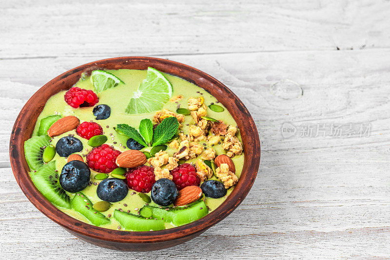 绿色冰沙碗抹茶与新鲜水果，浆果，坚果，种子为健康的素食饮食早餐
