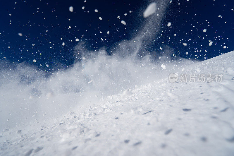 在晴朗的蓝天下，滑雪者在滑雪场溅雪的细节