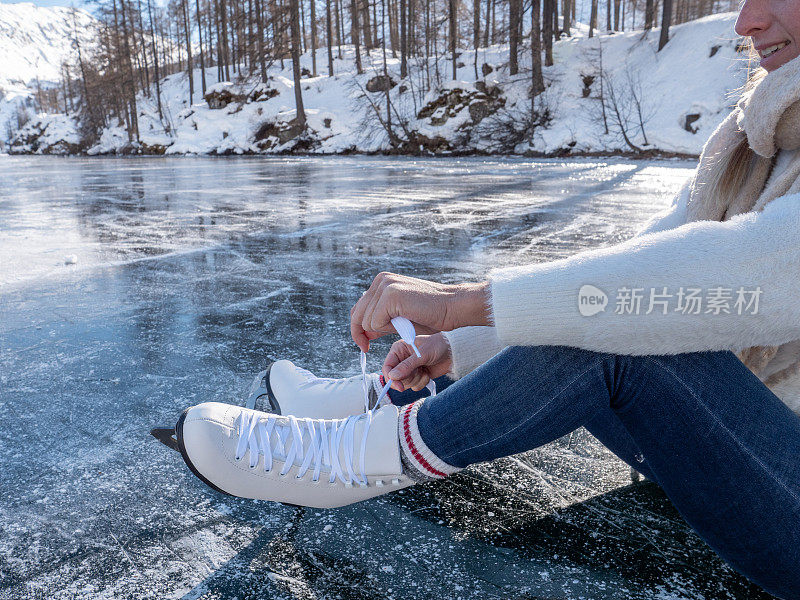 在结冰的湖面上整理冰鞋鞋带的女人