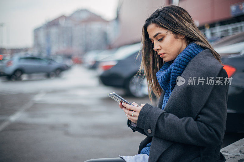 一名年轻女子在停车场上用智能手机