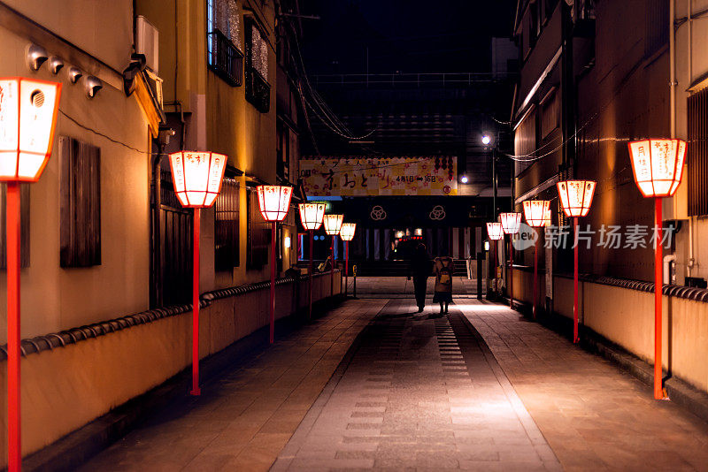 日本京都Gion区狭窄的小巷里，晚上有一对夫妇在散步，排着灯笼