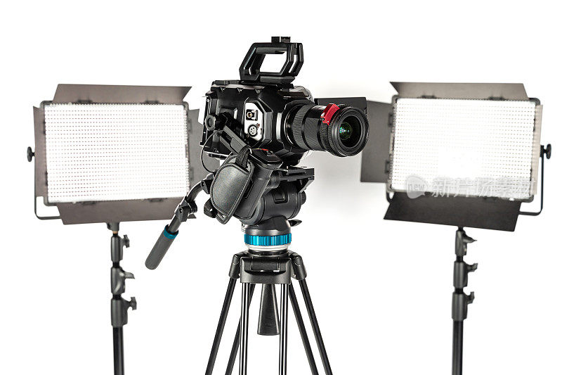 专业电影摄像机在一个摄像机三脚架和两个照明LED面板在白色工作室背景