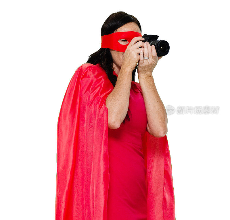 白人女摄影师站在白色背景前，穿着斗篷，拿着相机