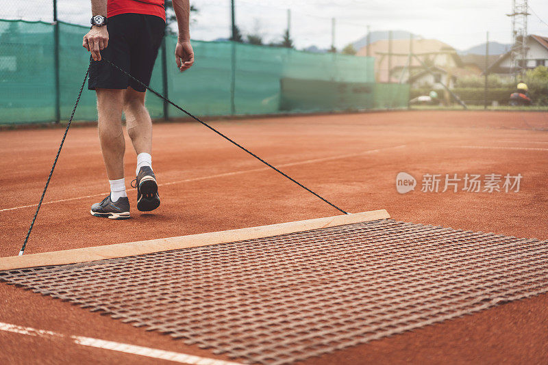 网球运动员拖着网穿过球场
