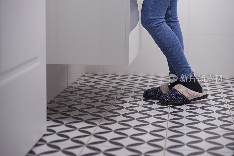 一个女人的脚踩在浴室的地砖上。