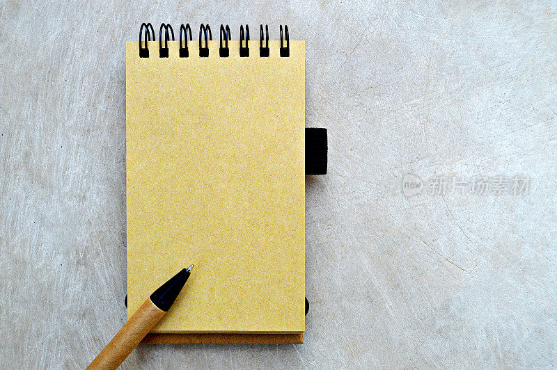 米色的素色页螺旋装订的记事本和一支钢笔