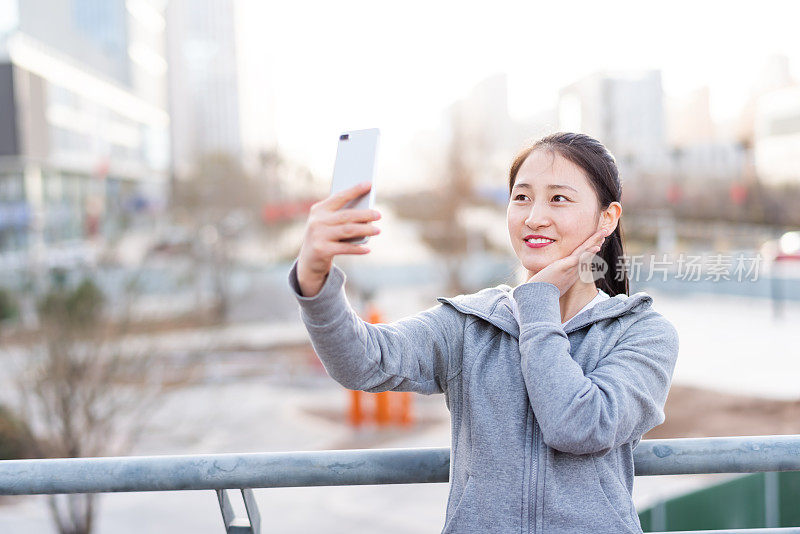 亚洲年轻女子在城市公共广场使用手机