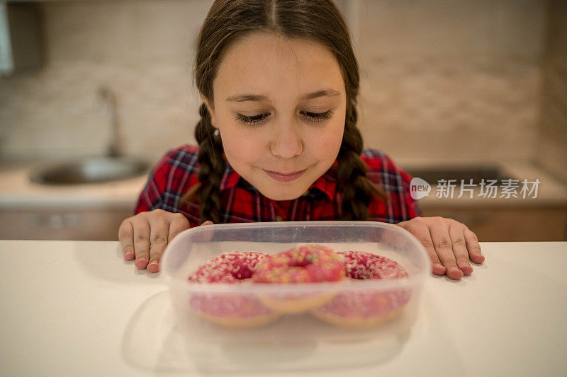 对孩子的饮食。悲伤和不快乐的孩子触及甜甜圈。孩子们的美味食物。孩子在看甜甜圈。垃圾食品上瘾。