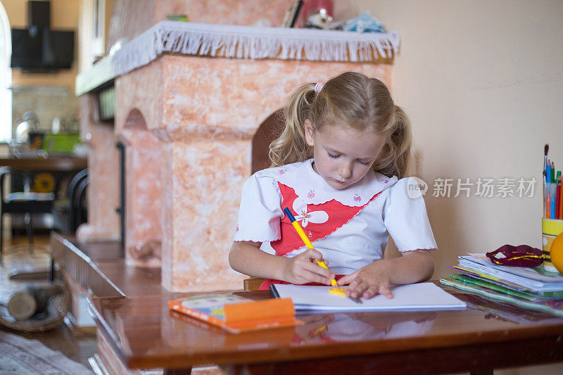 小女孩用铅笔在速写本上画画。
