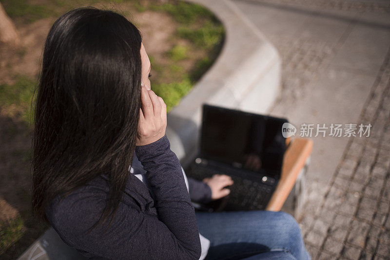 亚洲妇女使用笔记本电脑在长凳上库存照片