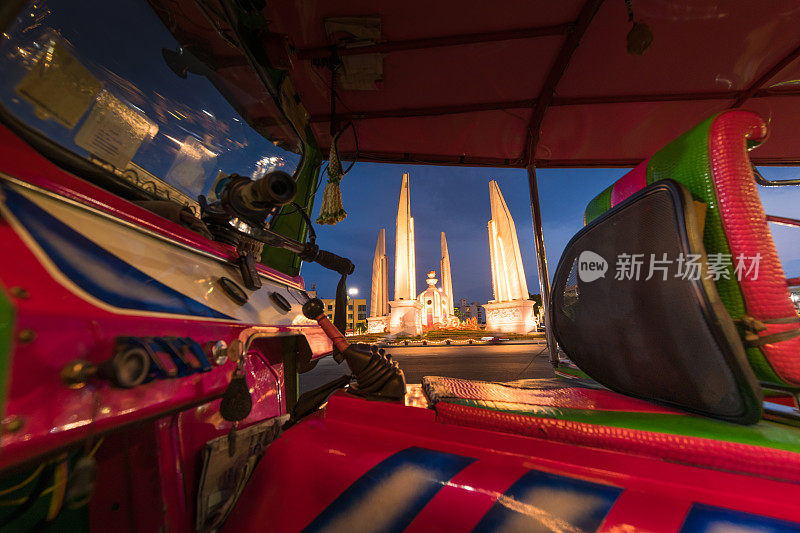 蓝色嘟嘟，泰国传统出租车停在泰国首都曼谷民主纪念碑的历史地标后，夕阳时分