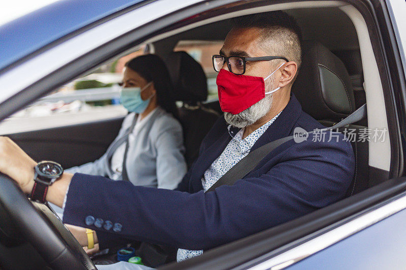 在隔离城市的一场疫情中，一男一女戴着防护面具坐在车里。
