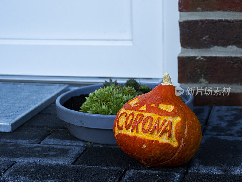 一个刻有corona字样的雕刻南瓜躺在一所房子的入口处
