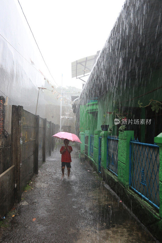 一个小女孩在倾盆大雨中带着雨伞。