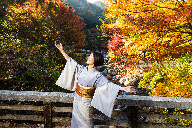 在小野的日本老年女子与秋天的枫叶跳舞