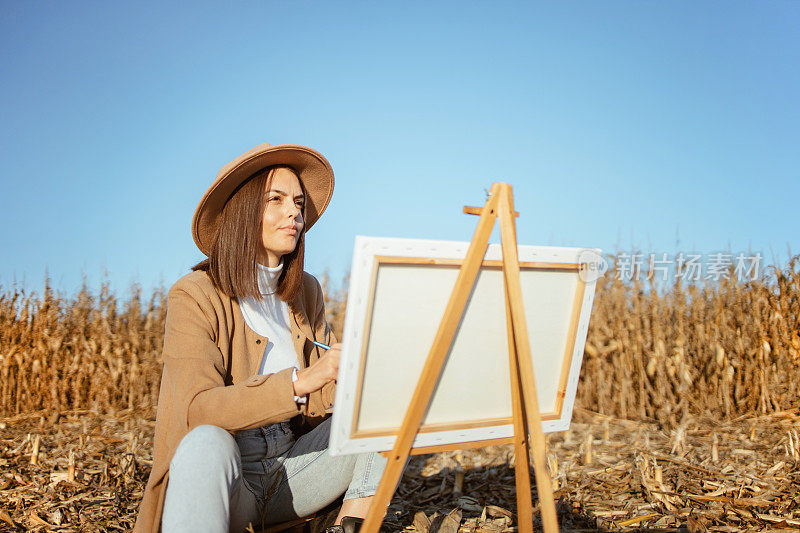 美丽的年轻女子在画布上描绘大自然