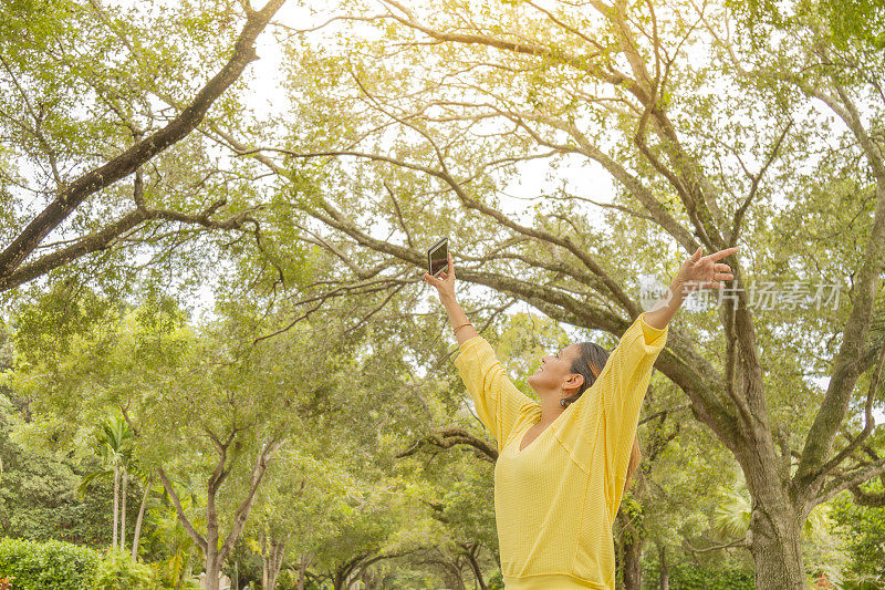 一位年轻的拉丁妇女在美国佛罗里达州迈阿密的珊瑚盖布尔斯街的树冠下享受旅行
