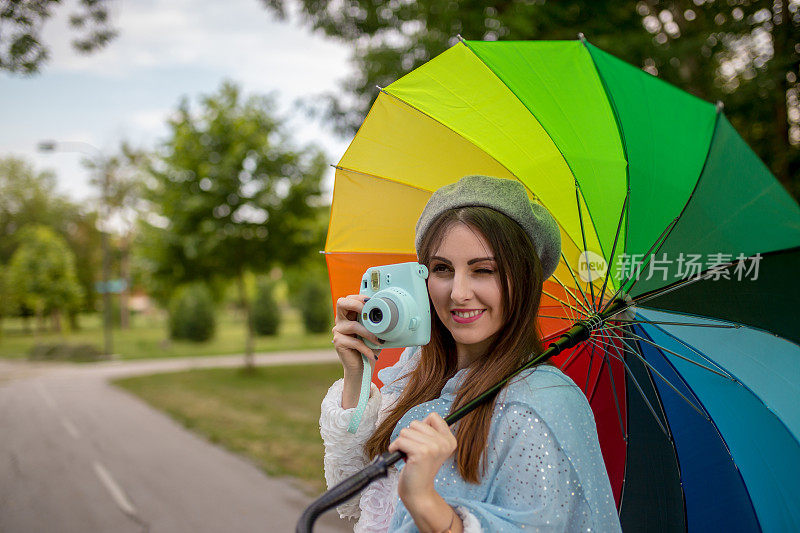 漂亮凉爽的女人带着五颜六色的雨伞在秋天的一天